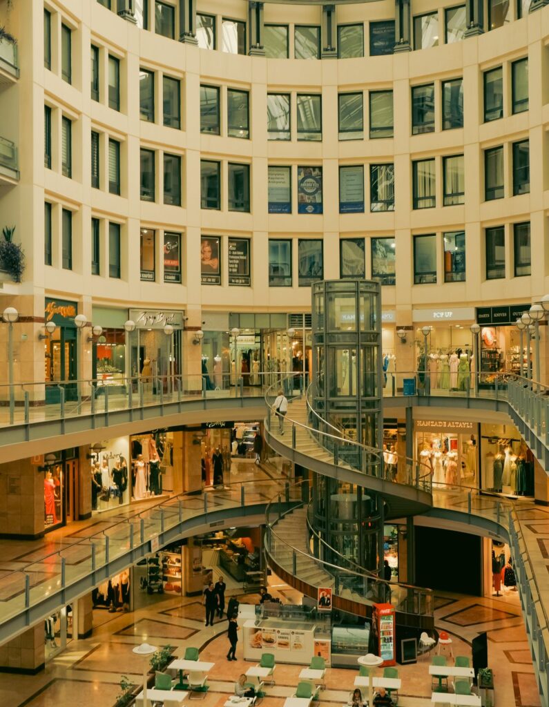 Interior de un centro comercial moderno con escaleras mecánicas y tiendas de retail