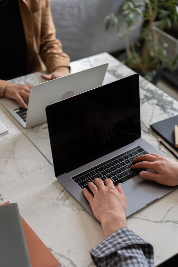 Manos escribiendo en el teclado de un portátil para publicar una vacante de retail